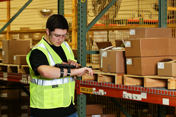 A male warehouse worker using a handheld device that is managed and secured by SOTI's MDM solution